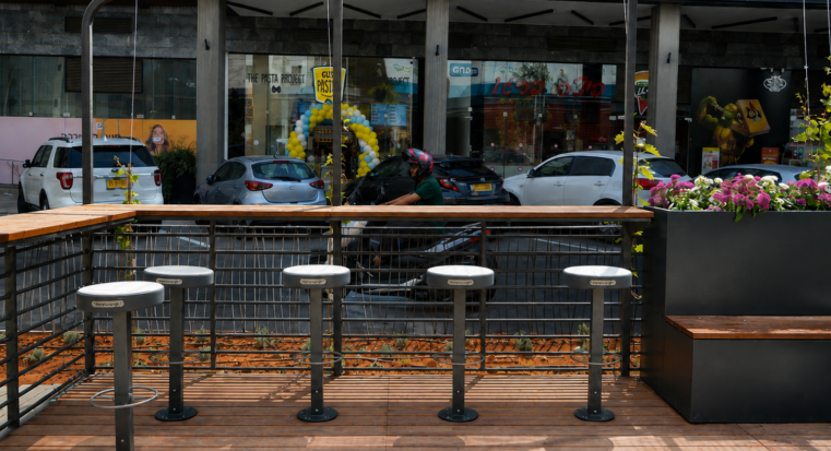 כיסאות בר שיזף מושב בטון ושולחן בר עץ משולב באדנית במרחב ציבורי